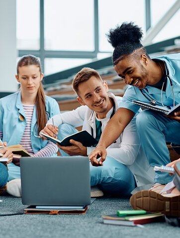 Group of happy medical students using laptop while learning in amphitheater.