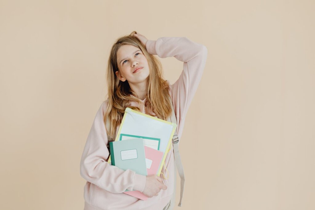 A Woman in Beige Long Sleeves Holding Notebooks